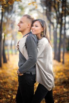 A young woman hugs her man from behind. Overprotection in family relationships.