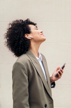 happy woman with wireless earphones smiles and enjoy listening music with her phone, concept of youth and technology, copy space for text