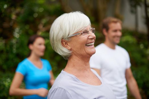 Keeping healthy and fit. a senior woman laughing outdoors with fellow fitness class members