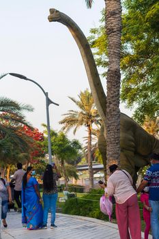 Dubai,UAE - 05.11.2021 -Visitors inspecting austrosaurus replica exhibit at dinosaur park.