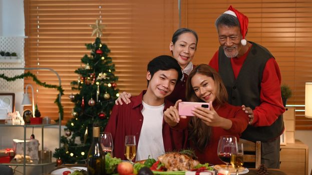 Happy family using smartphone and take selfie in room decorated for celebrating New year and Christmas festive.