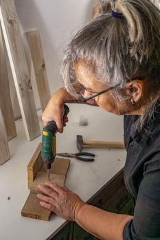 old woman working with power tools in her wood workshop