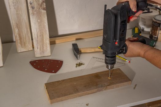 electric drill drilling wood in the workshop