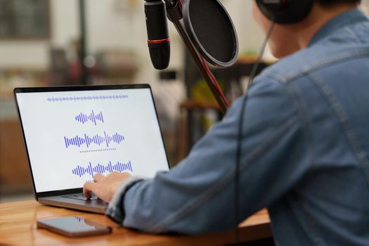 Podcaster editing audio podcast working at home studio.