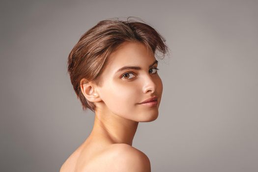 Beautiful young woman with absolutely no makeup on a neutral gray background.