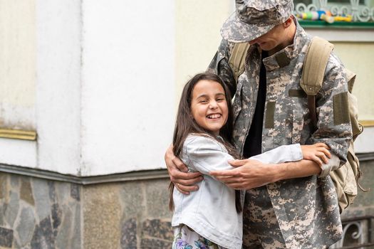 Soldier in camouflage meeting his daughter outdoors.