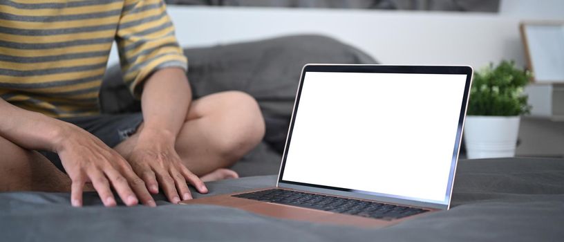 Mock up laptop computer with blank screen on bed.