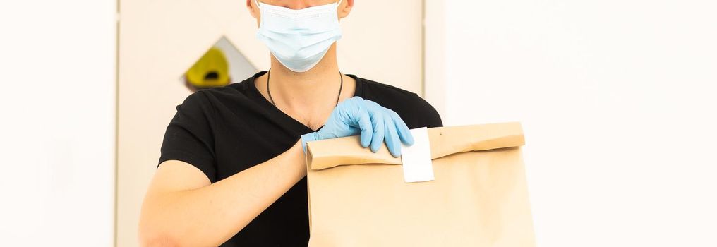 delivery man holding package to deliver. Courier hand holding brown box isolated on grey background. Detail of delivery man carrying cardboard parcel with label with copy space