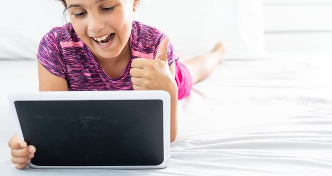 home, leisure, new technology and music concept - smiling little girl with tablet pc computer and headphones at home.
