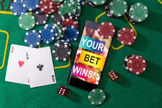 Smartphone and casino chips stacking on a green felt.