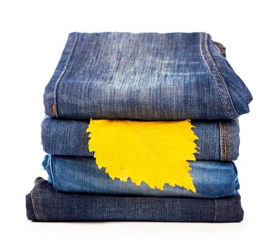 pile of jeans clothes and the form - a yellow autumn leaf