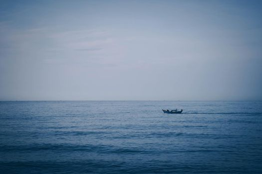 Simple background Calm dark blue sea fishing boat alone white pale Spindrift clouds Open way no limitations.