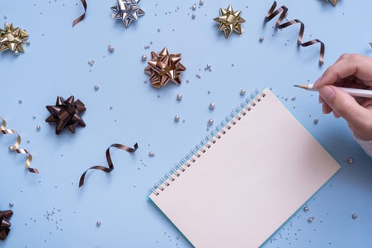 Tablet blank and pencil in female hand on bright festive background with bows and beads top view.