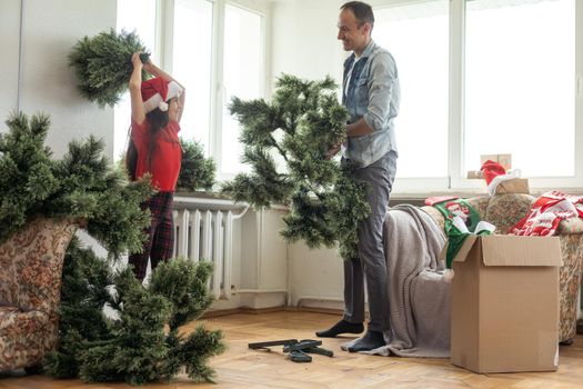 Father and daughter assembling christmas tree, smiling - christmas, holiday, winter concept, family activity