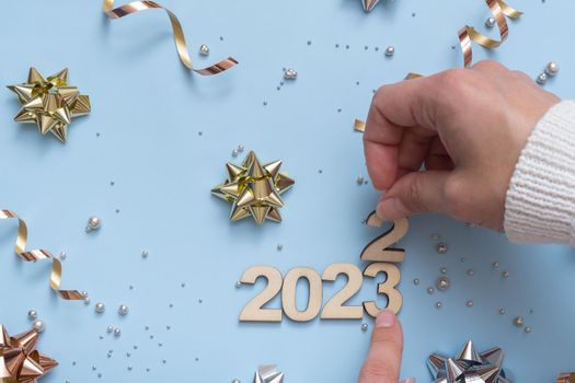 The numbers of the old year 2022 have been replaced by the new 2023 on a bright festive background of bows and beads, top view.