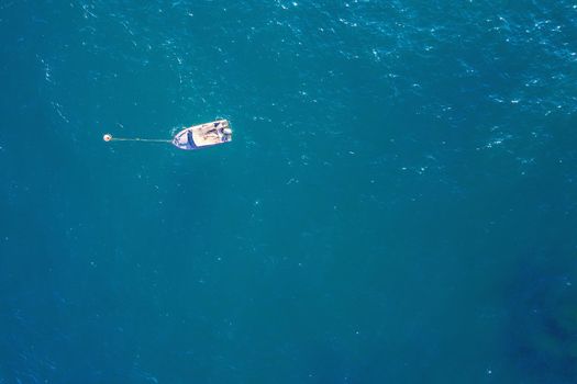 top view of a white boat moored in the blue sea in caribbean tropical beach with turquoise waters. concept of adventure lifestyle and water sports in summer holiday