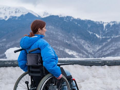 Caucasian woman in a wheelchair travels in the mountains in winter