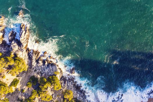 aerial top view of ocean beautiful sea waves crashing on the rocky island coast with spray and foam, concept of adventure lifestyle and summer holidays in the wilderness