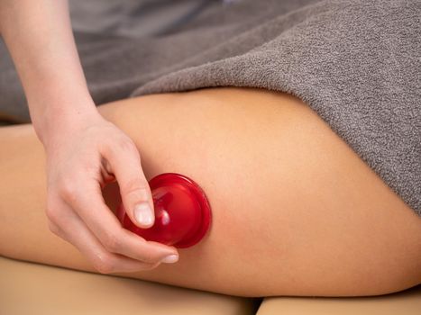 Woman on a session of anti-cellulite massage with a vacuum jar