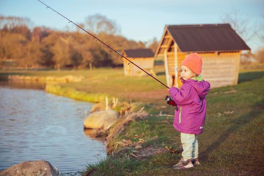 Charming baby fishing in the river at sunset.