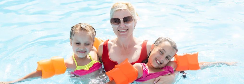 Happy family playing in blue water of swimming pool on a tropical resort at the sea. Summer vacations concept