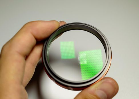 A child holding macro lens in a hand on a white background. Light reflection on a glass surface. High quality photo