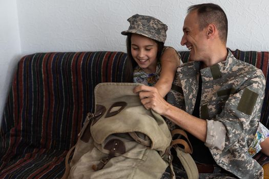 Little child is very happy her father came back from army. Little kid is hugging her father.