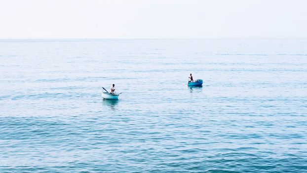 Simple background Calm dark blue sea fishing boats alone white pale Spindrift clouds Open way no limitations.
