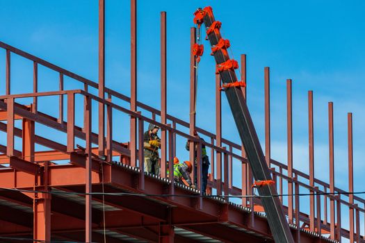 Builders fix iron beams with a crane. Frame construction. Moscow Russia April 14, 2022.