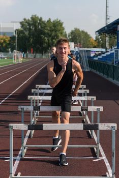 Young man athlete runnner running hurdles at the stadium outdoors