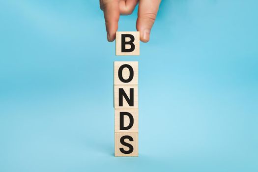 Concept of bonds. Businessman puts wooden blocks with the word Bonds. Equivalent loan. Unsecured and secured bonds. Bonds increasing concept. Copy space