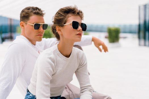 Young couple having problems in their relationship. man and woman friends in sunglasses sitting bench in city unhappy emotions. Relationships problem.