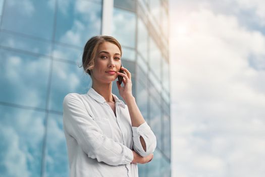 Businesswoman successful woman business person standing outdoor corporate building exterior cell phone Pensive elegance cute caucasian professional business woman middle age dreaming with mobile phone
