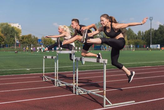 Two athlete woman and man runnner running hurdles at the stadium outdoors