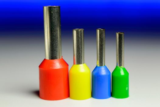 Four colorful ferrules standing in a row on a white background with a blue backlight - macro photo. High quality photo