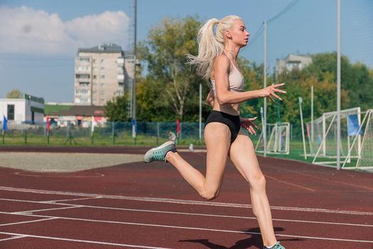 Young woman running on the running track at the stadium outdoors