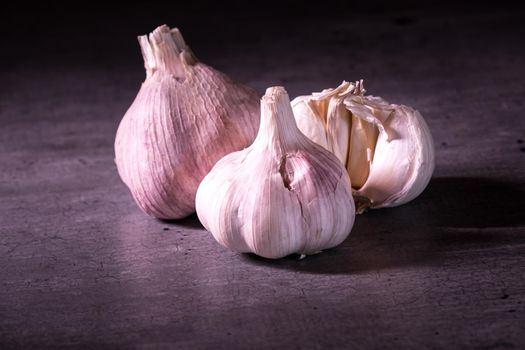 three large heads of pink garlic on a kitchen worktop