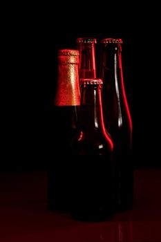 silhouettes of four beer bottles on a black background and lit with red light.