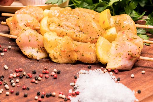 raw chicken skewers marinated with lemon on a wooden board