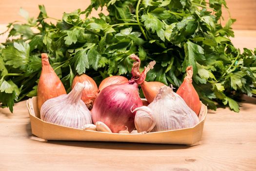 garlic onions shallots in a small wooden basket and parsley