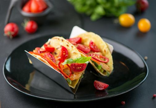 Spicy tacos with tomatoes and meat on a dark background
