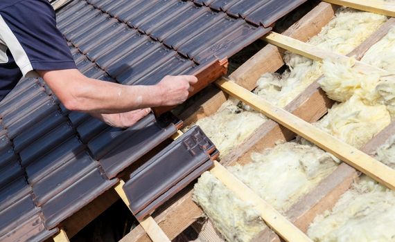 a roofer laying tile on the roof