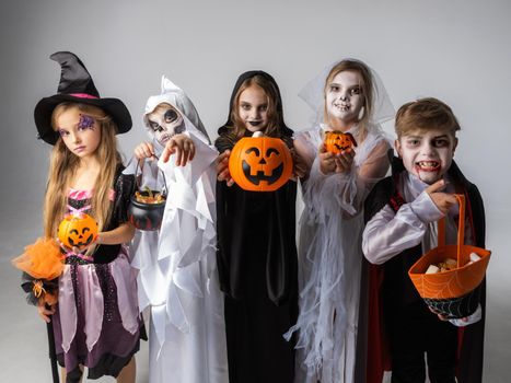 Group of children in costumes holding sweets at Halloween party