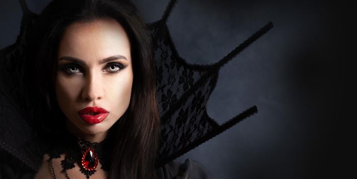 Halloween Vampire Woman portrait. Beautiful Glamour Fashion Sexy Vampire Lady with long black hair, beauty make up and costume