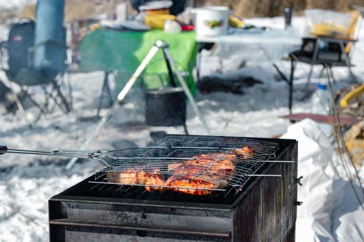 Winter barbecue party outdoors, grill steak meat over hot coals in BBQ at campsite cookout, close up view, camping mood