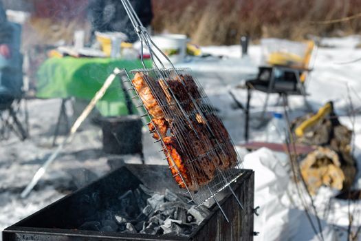 Winter barbecue party outdoors, grill steak meat over hot coals in BBQ at campsite cookout, close up view, camping mood