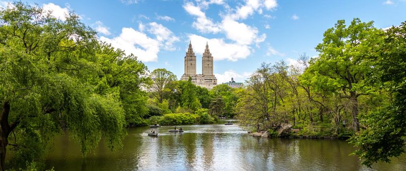 New york, USA - May 15, 2019: Row boats in lake in Central Park with skyscrapers in distance, Manhattan, New York city, USA