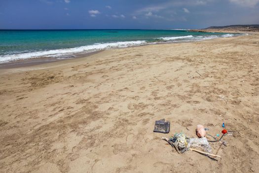 Beautiful wild natural beach, no people, calm azure sea in background, pile of garbage in foreground. Marine pollution concept.