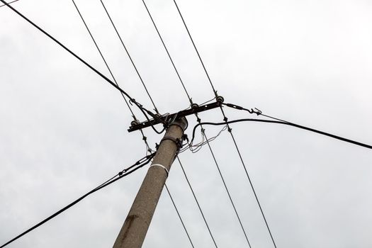 Small concrete pillar with power lines, overcast sky in background.