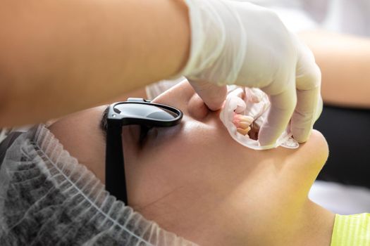 Patient with cheek retractor lying in dentist office in modern clinic